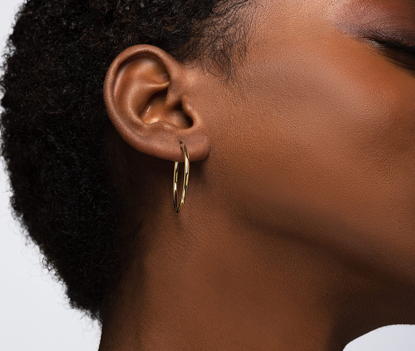 A woman wearing Birks Essentials gold hoop earrings.